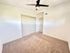 Bright bedroom with fresh carpeting, ceiling fan, and ample closet space.