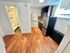Modern apartment kitchen with sleek stainless steel appliances and adjacent cozy bathroom, enhanced by warm wooden floors.
