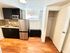 Charming kitchen space with modern stainless steel fridge, sleek built-in microwave, and elegant wooden flooring. Perfect for cozy cooking sessions.