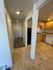 Bright hallway leading to a cozy kitchen with wooden cabinets and tiled floors, offering a welcoming space.