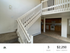 Inviting apartment with three bedrooms, featuring a modern open staircase, cozy carpeted area, and a spacious kitchen with wooden cabinetry.