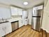 Modern kitchen with stainless steel appliances, sleek white cabinets, and elegant wood flooring, offering a stylish and functional space.