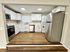 Modern kitchen featuring sleek white cabinetry, stainless steel appliances, and integrated laundry area, with warm wood flooring and ample natural light.