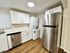 Modern kitchen with sleek stainless steel appliances, elegant white cabinetry, and integrated washer-dryer, perfect for convenient urban living.