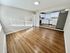 Bright, open-concept living space with elegant wooden flooring and a modern kitchen, featuring sleek white cabinets and stainless steel appliances.