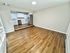 Modern open-plan kitchen and living area featuring sleek white cabinetry, stainless steel appliances, and elegant wood flooring.
