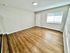 Bright and inviting room with sleek hardwood flooring, modern lighting, and ample natural sunlight through a large window.