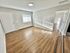 Bright and spacious living area with sleek hardwood floors, soft gray walls, and abundant natural light from large windows.
