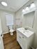 Modern bathroom featuring elegant lighting, sleek vanity with ample storage, and classic hardwood flooring for a cozy touch.