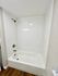 Modern bathroom featuring a sleek white bathtub, stylish tiles, and wood-style flooring.