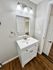 Contemporary bathroom with elegant vanity, sleek mirror, and chic lighting, accented by warm wooden floors.