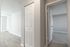 Bright and airy apartment hallway with laminate wood flooring and white doors leading to spacious rooms.