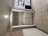 Modern laundry space with washer and dryer in a tiled kitchen area, featuring ample storage and sleek cabinetry.