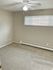 Bright and airy bedroom with soft beige carpet, large window with blinds, and a ceiling fan for optimal comfort.