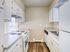 Charming kitchen with sleek white cabinetry, modern appliances, and natural light accentuating the cozy space.