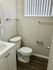 Bright and modern bathroom with sleek fixtures, white cabinetry, and elegant window blinds.