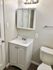 Modern bathroom with sleek white vanity, mirrored cabinet, and bright lighting.