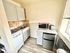 Cozy kitchen with modern appliances, featuring a compact stove, microwave, and mini fridge set against a warm tiled backsplash.