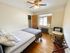 Cozy and inviting bedroom with a ceiling fan, plush bedding, and natural light from a large window.