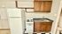 Compact kitchen with white appliances, sleek countertop, and warm wood cabinetry, perfect for cozy cooking moments.