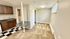Cozy apartment space with a compact kitchenette featuring wooden cabinetry and a dual sink, alongside a small bar table in a bright room with large windows.