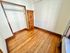Bright room with polished hardwood floors, featuring a spacious closet and classic wooden door, perfect for storage or a cozy corner.