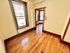 Charming sunlit room with warm wooden floors and classic trim, leading to a bright and inviting adjacent space.