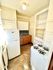 Charming compact kitchen with natural light, gas stove, spacious fridge, and elegant tile flooring.