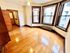 Bright and inviting room with polished hardwood floors and large windows, offering a cozy and elegant living space.
