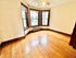 Bright corner room featuring elegant hardwood floors and large windows with charming wooden trim.