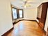 Bright, cozy room with hardwood floors, large windows, and elegant built-in wooden cabinet.