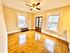 Bright and inviting room with polished hardwood floors, large windows, and a modern ceiling fan.