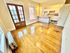 Charming apartment with glossy hardwood floors, bright kitchen, and vintage French doors opening to a vibrant urban view.