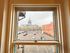 Charming apartment window view showcasing a historic building with golden dome, surrounded by parked cars and a classic red-brick structure.