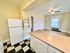 Charming open-concept kitchen and living area with checkered floor, fridge, and large window letting in natural light.