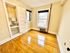 Charming room with polished hardwood floors, adjacent compact bathroom, and abundant natural light from large windows.