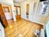 Charming bedroom with polished hardwood floors, built-in wooden wardrobe, and a cozy window view, inviting natural light and warmth.