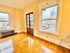 Bright room with gleaming hardwood floors, large windows offering a stunning cityscape view, and elegant French doors.