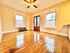 Bright and inviting living room featuring polished hardwood floors, large windows with cityscape views, and a charming ceiling fan.