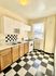 Charming kitchen with classic black-and-white checkered flooring, wooden cabinets, and sleek white appliances.