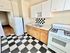Charming kitchen with checkerboard flooring, white cabinetry, and a classic gas stove. Bright and inviting space perfect for culinary adventures.