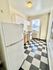 Bright kitchen with retro black-and-white checkered flooring, modern white cabinets, and a cozy atmosphere.