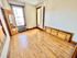 Bright and cozy room with polished hardwood floors, natural light from large windows, and classic wooden trim. Ideal for a comfortable and inviting living space.