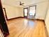 Bright and spacious room with hardwood floors, large window, and ceiling fan, ideal for a cozy living space.
