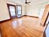 Spacious and sunlit room with elegant wooden floors, classic wooden door, and large windows with blinds, perfect for a comfortable living area.