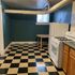 Charming kitchen with retro black and white tiled floor, sleek white appliances, and deep blue walls creating a cozy atmosphere.