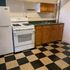 Charming kitchen with classic black and white checkered floor, wooden cabinets, and modern white appliances.