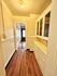 Inviting hallway with warm wood flooring and chic built-in cabinets, leading to a sunlit room.