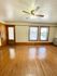 Charming bright room with polished hardwood floors, elegant ceiling fan, and large windows providing natural light.