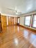 Bright and spacious room with polished hardwood floors, large windows, and charming wooden doors.